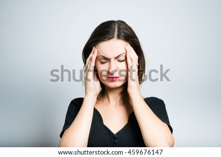 young woman has a pain temples, studio photo isolated on a gray background
