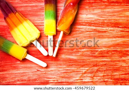 Colorful ice lolly on a red wooden background