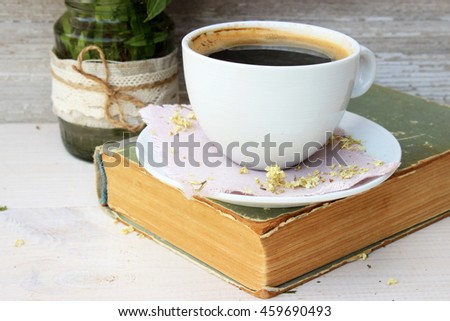 Full light composition with cup of fresh tasty coffee, vintage book with yellow shabby cover and paper. Concept for beautiful romantic morning theme