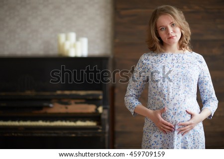 pregnant woman in a white dress near piano