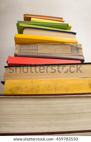 Composition with vintage old hardback books, diary, fanned pages on wooden deck table and beige background. Books stacking. Back to school. Copy Space. Education background.