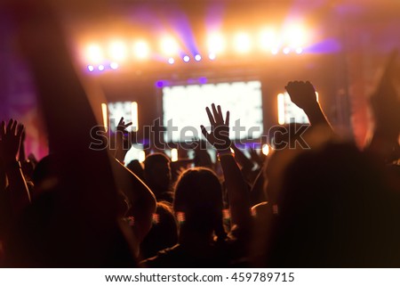People enjoying a concert and holding their hands up.