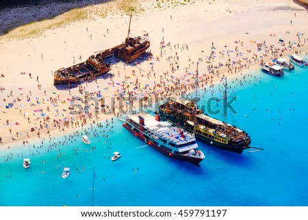 Boats anchored at Navagio beach, Zakynthos. Famous shipwreck on the beach and tourist bathing in the sun.