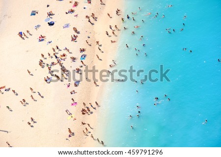 People bathing in the sun, swiming and playing games on the beach. Tourists on the sand beach of Navagio Zakynthos Greece. Royalty-Free Stock Photo #459791296