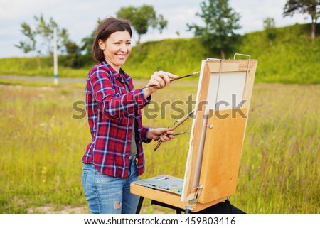 happy painter paints a picture in nature