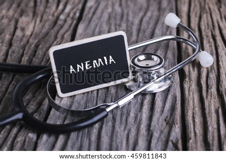Medicine concept. Blackboard with word ANEMIA and stethoscope on wooden background.