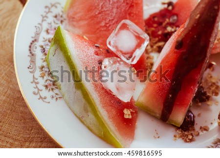 Frozen watermelon chocolate in a dish with ice on a wooden table