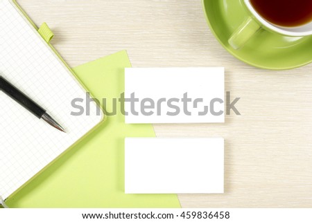 Business card blank, notepad, coffee cup and pen at office desk table top view. Corporate stationery branding mock-up