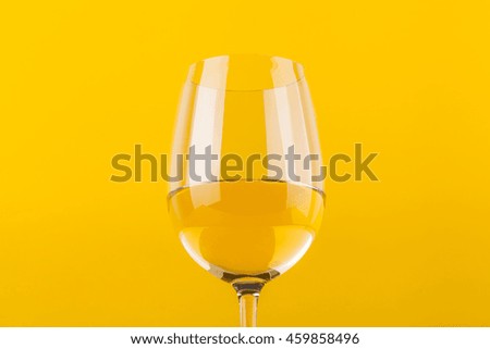 Glass of white wine over a vivid yellow background