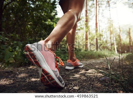 Close-up of female hiker feet walking on forest trail. Active woman backpacker traveling on the nature.  Royalty-Free Stock Photo #459863521