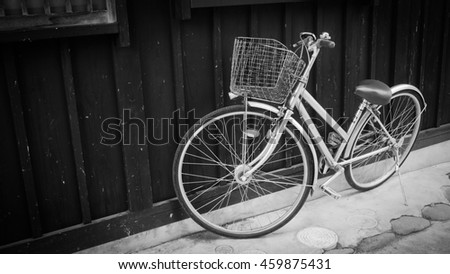 Retro bicycle with basket in front of the Wood wall, black and white