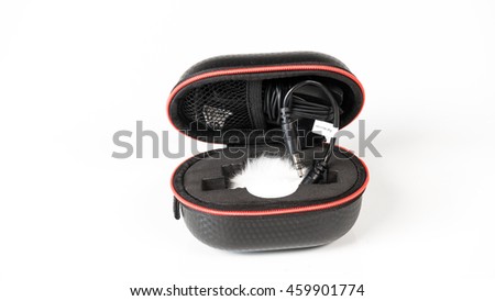 Small zipped case box with black color small tie-clip on microphone lapel or lavalier. Isolated on white background. Slightly de-focused and close-up shot. Copy space.