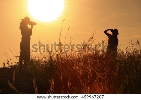 couple take a photograph during sunset.