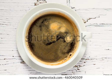 white cup of coffee on the white wooden table. top view. center of the frame