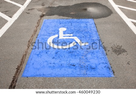 Painted handicapped symbol on decaying asphalt.