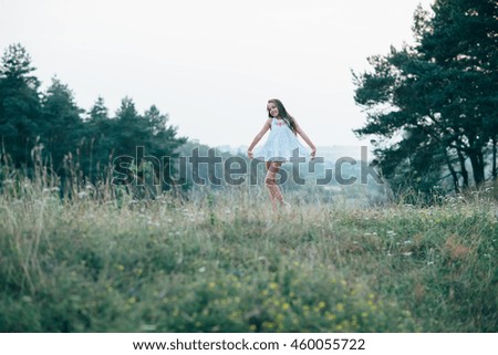 Little cutie girl in a white dress dancing in the woods