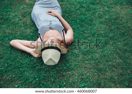 Young fashion trendy hipster girl in dress relaxing on the grass outdoors.