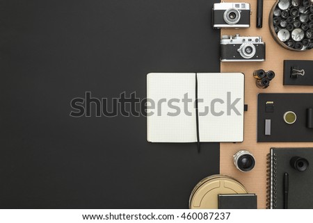 Black desk of photographer. Workspace on black table of a creative designer or photographer with laptop, tablet, cameras other objects of inspiration and copy space. Stylish home studio concept.