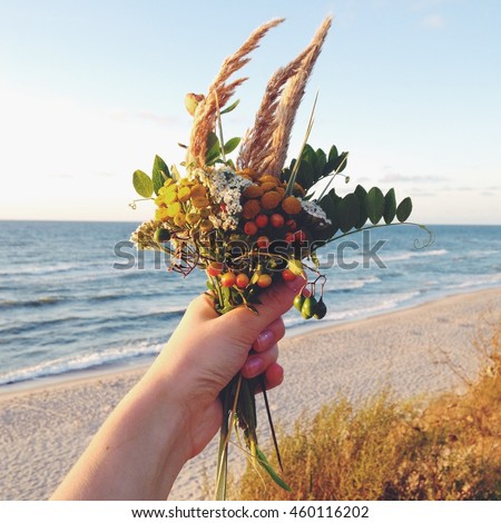 beautiful autumn bouquet on background of the Baltic Sea in the hand. dried herbs, berries. dried flowers. photo shot on your phone