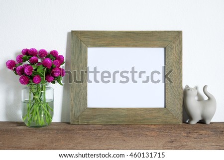 mock up of blank photo frame with pink flowers on wooden shelf.
