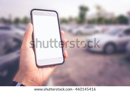 Smart phone with white screen in hand on blurred Parking background