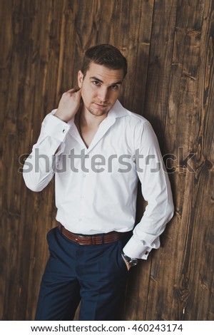 Portrait of a man in a white shirt in the background of a wooden wall.