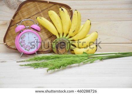  Alarm clock and banana on white wood background
