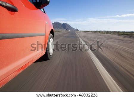 Red car driving through the country at high speed
