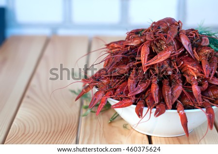 Boiled crayfishes with greenery on a plate in the table