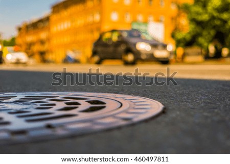 Summer in the city, the car rides on the avenue. Close up view of a hatch at the level of the asphalt