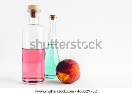 Bottles With Coloured Liquid On The White Background And A Peach 