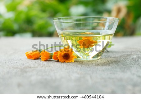 calendula essential oil container with calendula flowers on wooden background