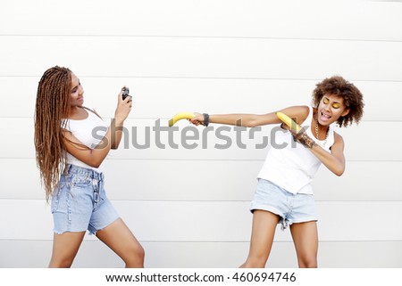 Young naughty african girls having fun. Outdoor lifestyle portrait of two best friends hipsters making photo on their vintage camera, together, joy and happiness, wearing trendy clothes