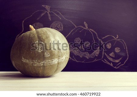 Green pumpkin with a smile on blackboard painted with chalk cheerful pumpkins / concept Happy Halloween
