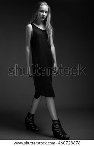 fashion model with long hair,perfect skin is posing in studio for glamour test photo shoot showing different poses. Picture taken in the studio on a gray background. Black and white photo