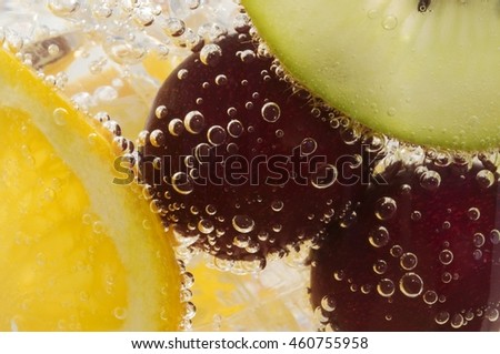 Beautiful cherries, orange and kiwi in water with bubbles