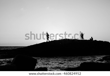 Silhouettes of people on rock, Sunset at sea in Thailand,Black and white