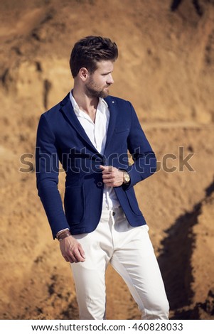 A handsome man in a dark blue jacket against the desert