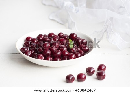 Burgundy cherries in the white saucer on the window-sill. The gifts of summer.