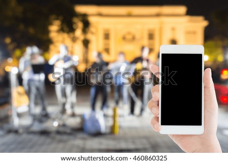 woman use mobile phone and blurred image of a band on the street market at night
