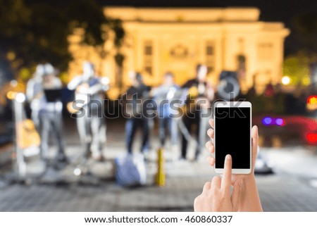woman use mobile phone and blurred image of a band on the street market at night