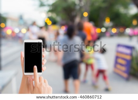 woman use mobile phone and blurred image of people on the street market 