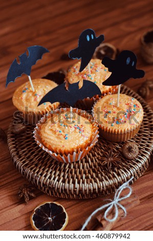 Halloween orange sprinkled cupcakes with pumpkin cheese cream and scary ghost and bat decorations