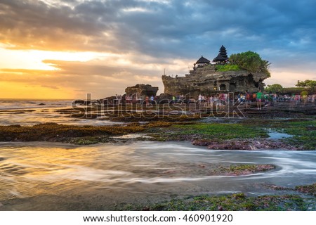 Tourist crowd walk into the see to Pura Tanah lot , Hindu temple that is one of the most favourite dramatic sunsets scene of Bali. Royalty-Free Stock Photo #460901920