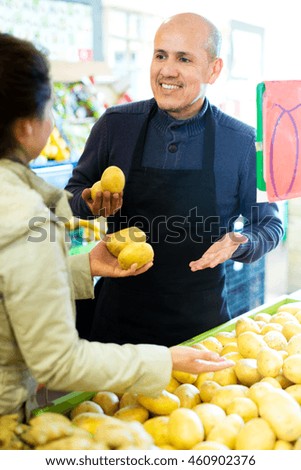 Portrait cheerful worker selling vegetables to female young customer 