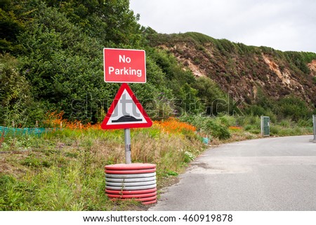 No Parking and Humps in Road Sign. Public Warning or Information Notice. Road and Entrance in Background.
