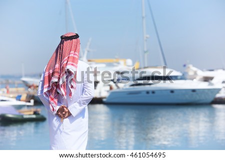 Arabian man looking at the yacht harbor, back view Royalty-Free Stock Photo #461054695