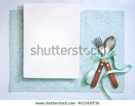 Floral pattern turquoise colour napkin background with cutlery set tide with ribbon. Dinner invitation card design background text space image.