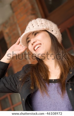 Attractive Asian girl smile in white hat on old street.
