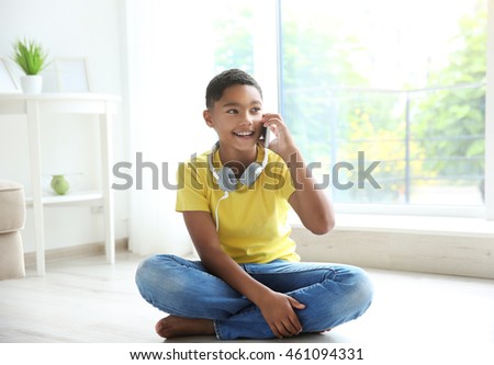 African American boy with headphones and cellphone at home
